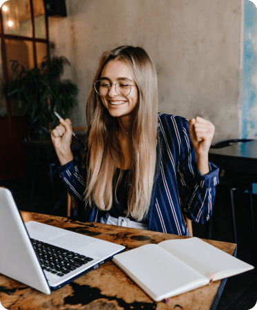 Mujer dueña de una empresa celebrando y sonriendo por una transacción de un pago exitoso, frente al notebook. 